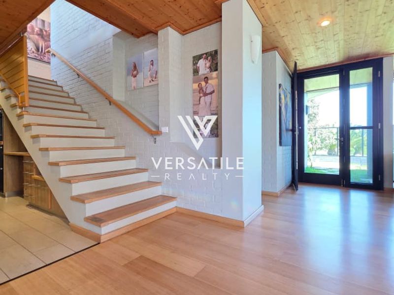 Spacious entrance hall featuring timber ceiling, timber staircase with matching handrail, and light timber flooring, leading to double glass doors.