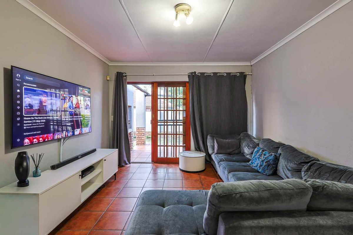 A comfortable living room featuring terracotta floor tiles and a wooden framed glass door providing direct access to the outdoor patio area.