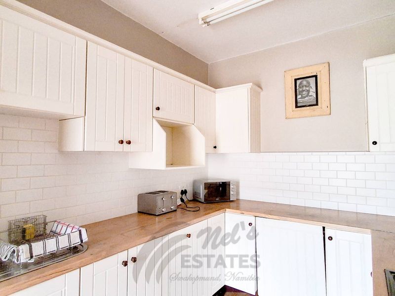 A bright kitchen featuring white shaker-style cabinetry, a classic subway tile backsplash, and warm butcher block countertops.