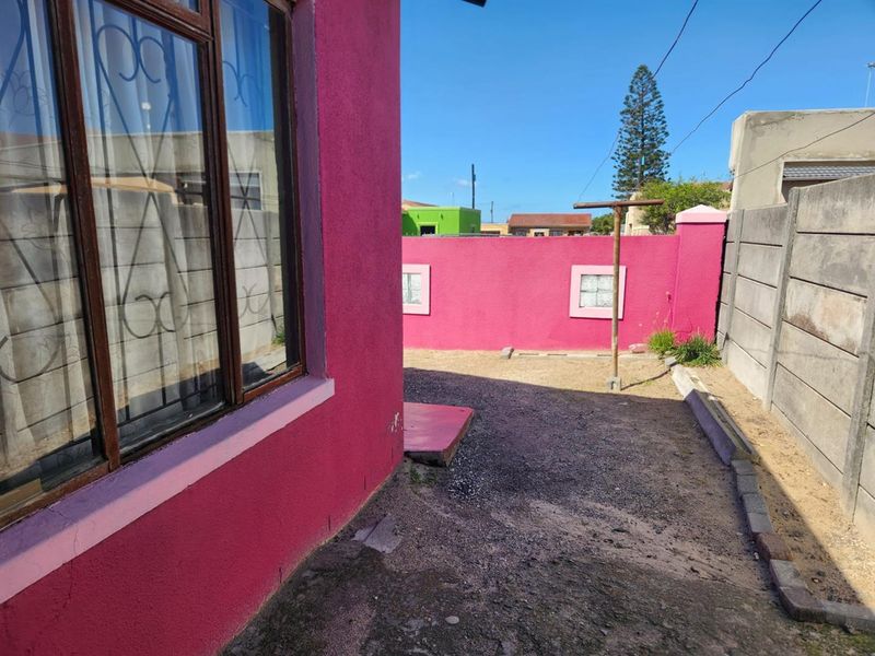 Rear exterior area featuring a precast concrete boundary wall, fixed washing line, and access to the main dwelling with security-barred windows.