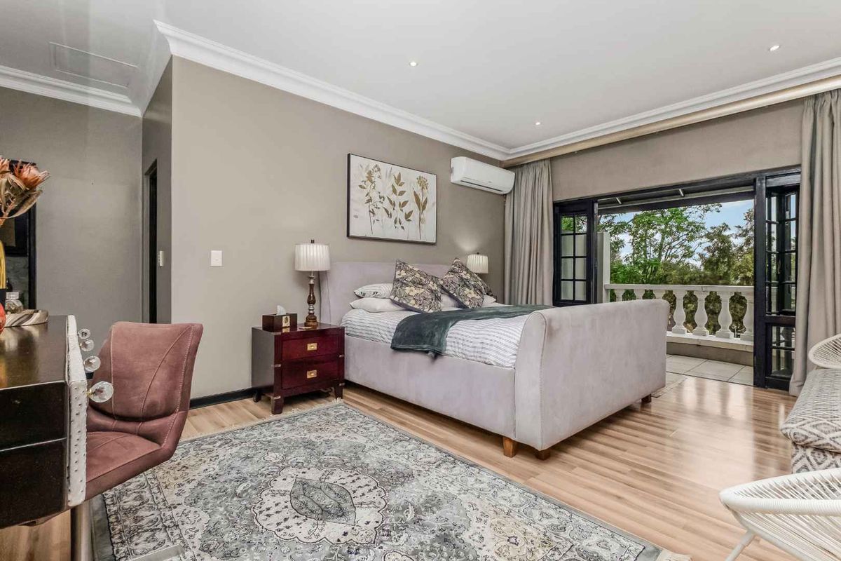 Spacious bedroom featuring laminate flooring, crown molding, recessed lighting, and direct access to a private balcony through double doors.