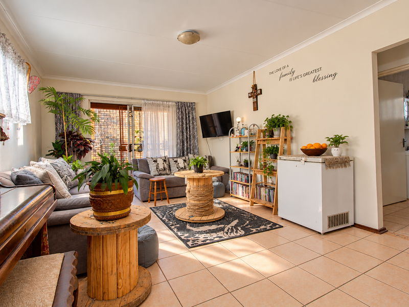 A spacious living room featuring tiled flooring, coved ceilings, and a sliding glass door providing access to the outdoor area.