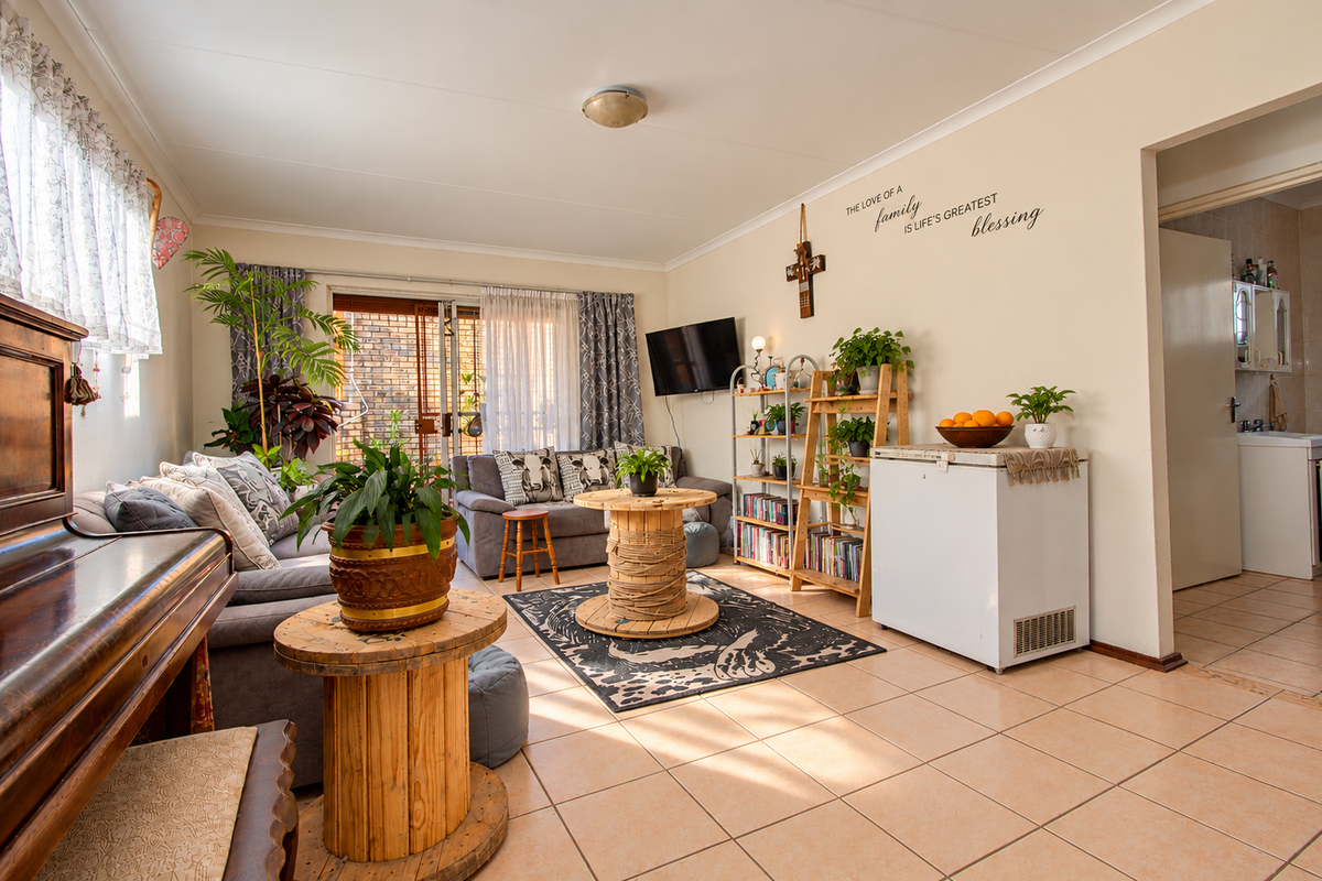 A spacious living room featuring tiled flooring, coved ceilings, and a sliding glass door providing access to the outdoor area.