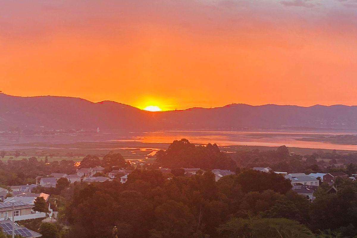 A scenic sunset view overlooking the surrounding landscape, estuary, and residential neighborhood.