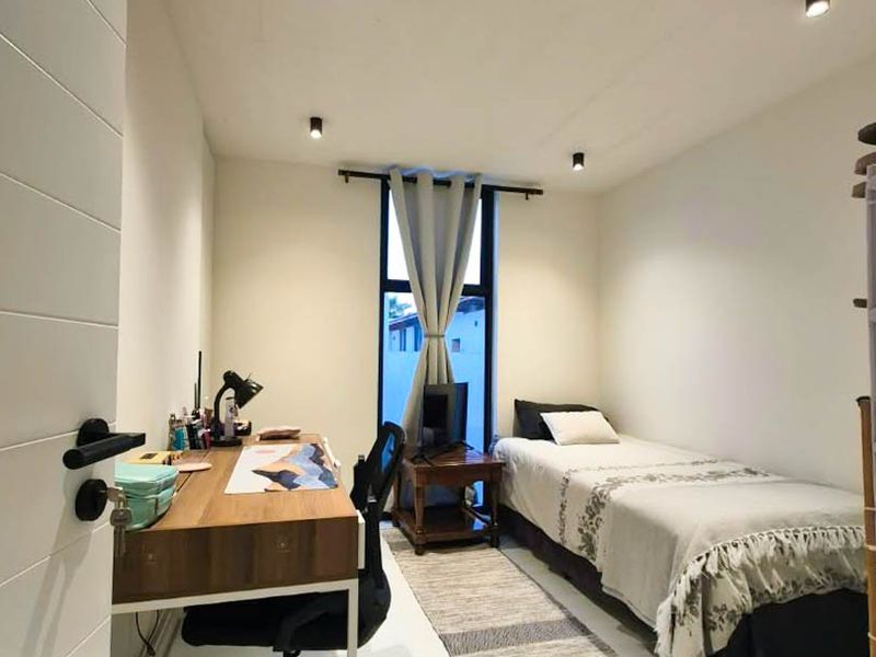 A well-lit bedroom featuring modern recessed ceiling spotlights, laminate flooring, and a full-height window providing natural light.