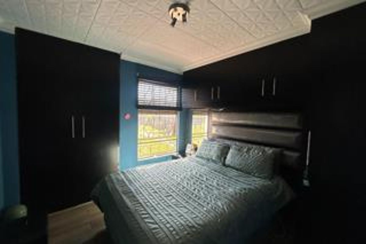 A bedroom featuring built-in dark cabinetry, overhead storage units, and a textured ceiling finish.