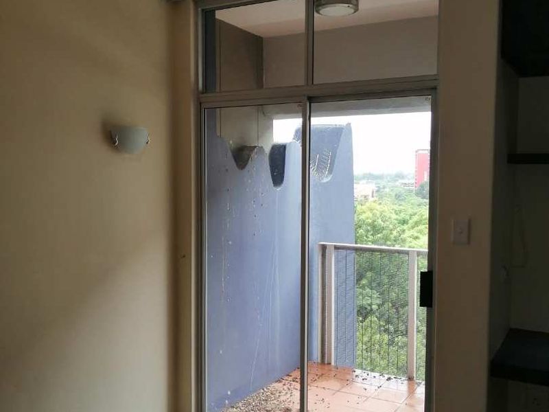 A vacant bedroom featuring carpeted flooring and a sliding glass door providing direct access to a private balcony with outdoor views.