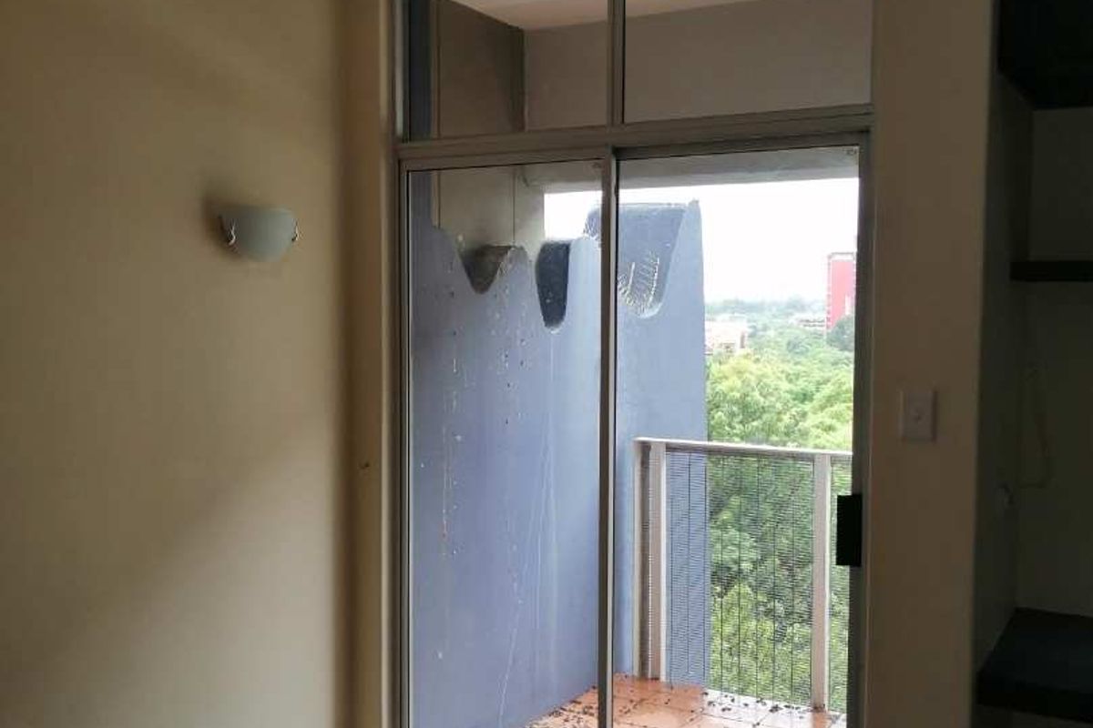 A vacant bedroom featuring carpeted flooring and a sliding glass door providing direct access to a private balcony with outdoor views.