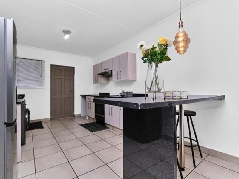 Functional kitchen featuring built-in cabinetry, granite countertops, a breakfast bar, and tiled flooring, providing a practical space for cooking and casual dining.