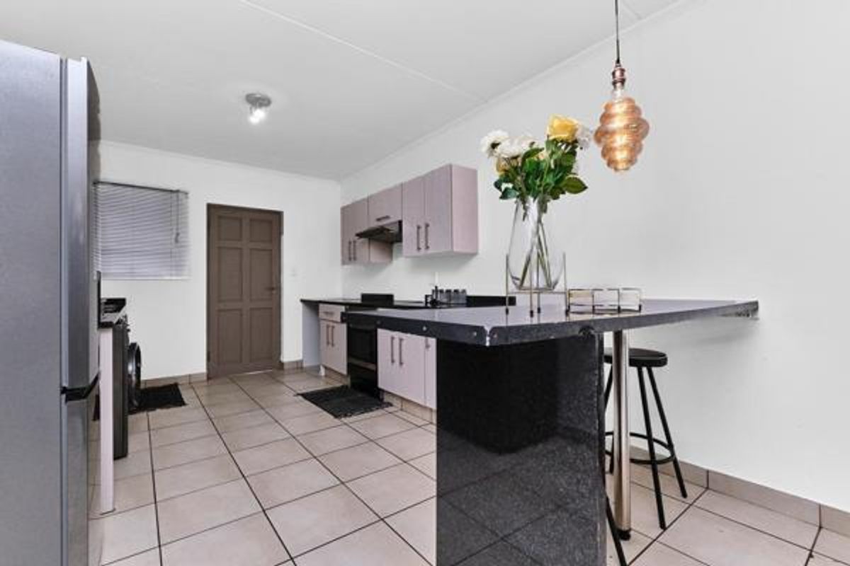 Functional kitchen featuring built-in cabinetry, granite countertops, a breakfast bar, and tiled flooring, providing a practical space for cooking and casual dining.