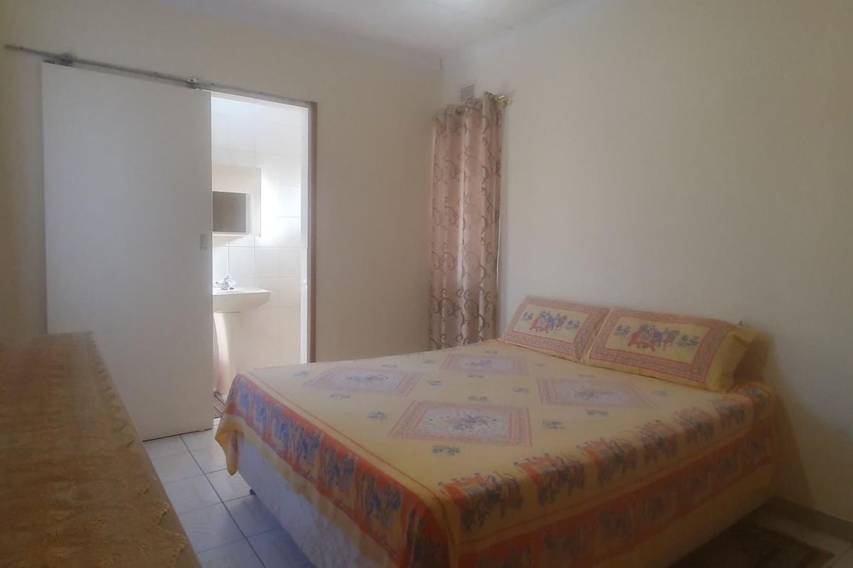 A functional bedroom featuring tiled flooring and direct access to an en-suite bathroom through a sliding door.