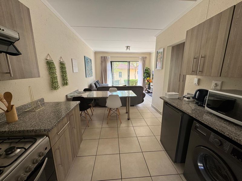 Open-plan kitchen and living area featuring granite countertops, modern cabinetry, and tiled flooring, leading to a sliding door with access to the exterior.
