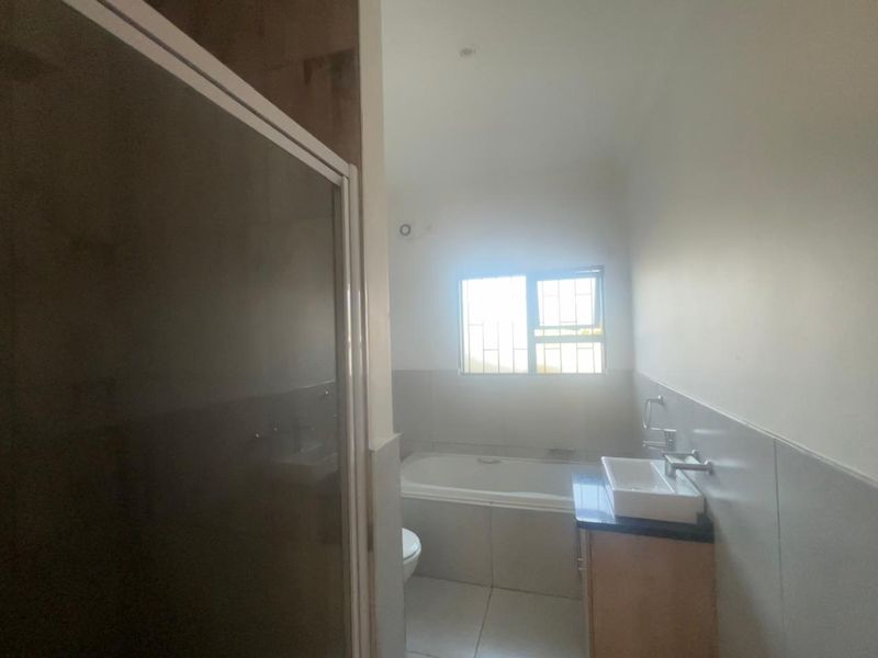 A functional bathroom featuring a built-in bathtub, a vanity with a vessel sink, and a separate shower enclosure with tiled finishes.