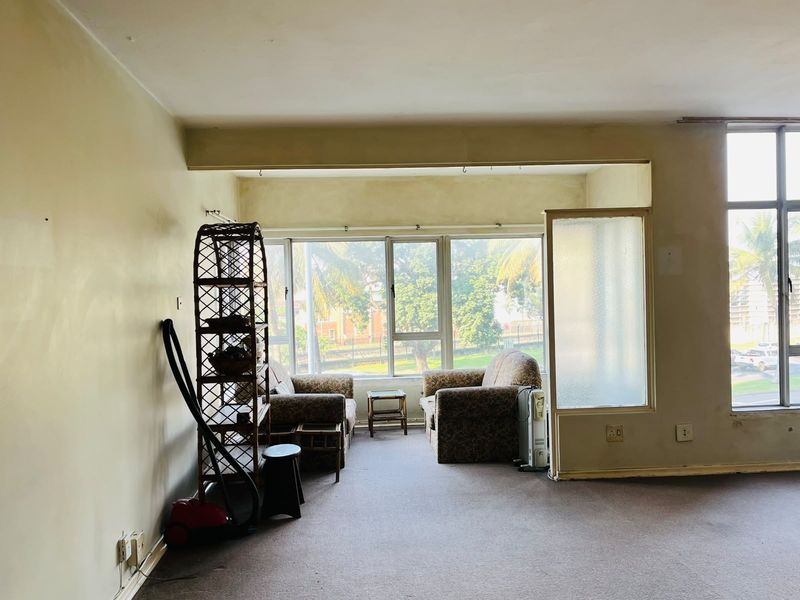 Spacious living area featuring large windows that provide ample natural light, carpeted flooring, and a unique frosted glass partition.
