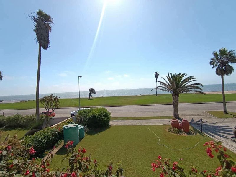 A scenic elevated view overlooking a manicured garden, coastal road, and the ocean horizon.