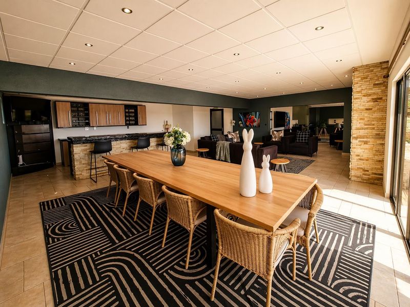 Spacious open-plan living and dining area featuring a built-in bar, stone veneer accents, recessed lighting, and large sliding doors leading to the outdoors.