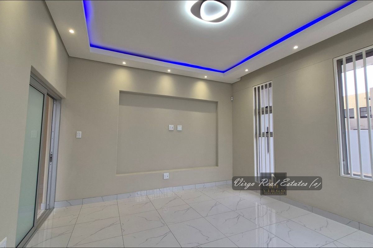 Modern living room featuring tiled flooring, a recessed television niche, and a stylish ceiling with integrated LED accent lighting.