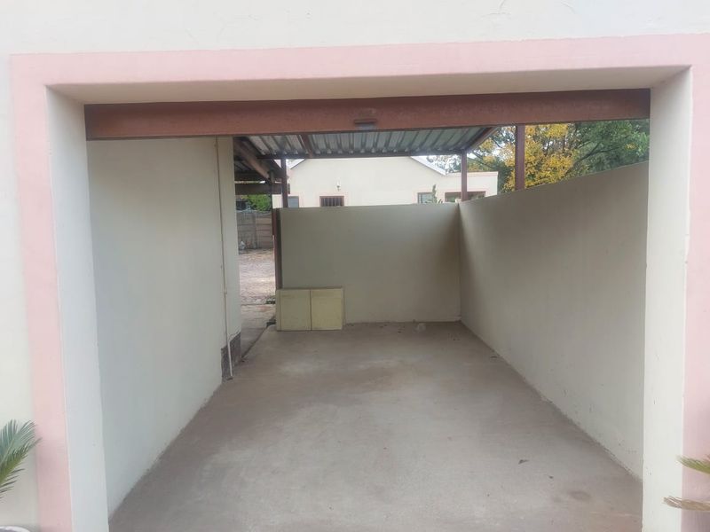 An open-plan garage space featuring a concrete floor and corrugated metal roofing, providing basic covered parking or utility storage.