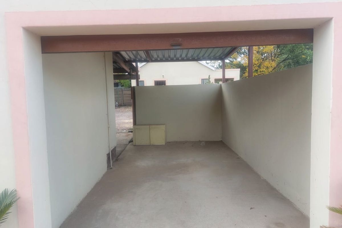 An open-plan garage space featuring a concrete floor and corrugated metal roofing, providing basic covered parking or utility storage.