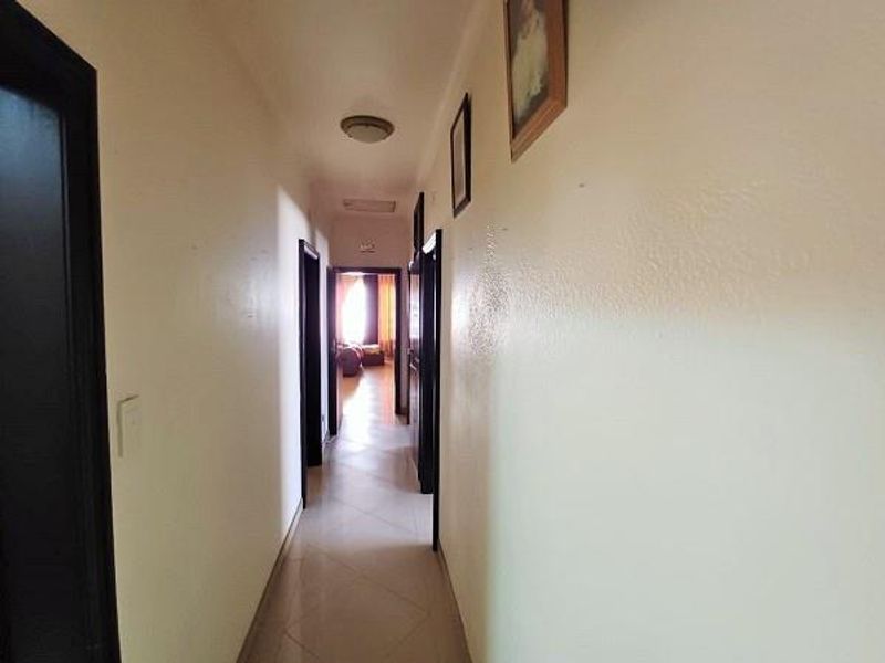 A functional residential hallway featuring tiled flooring and multiple access points to adjoining rooms, providing a central circulation space within the home.