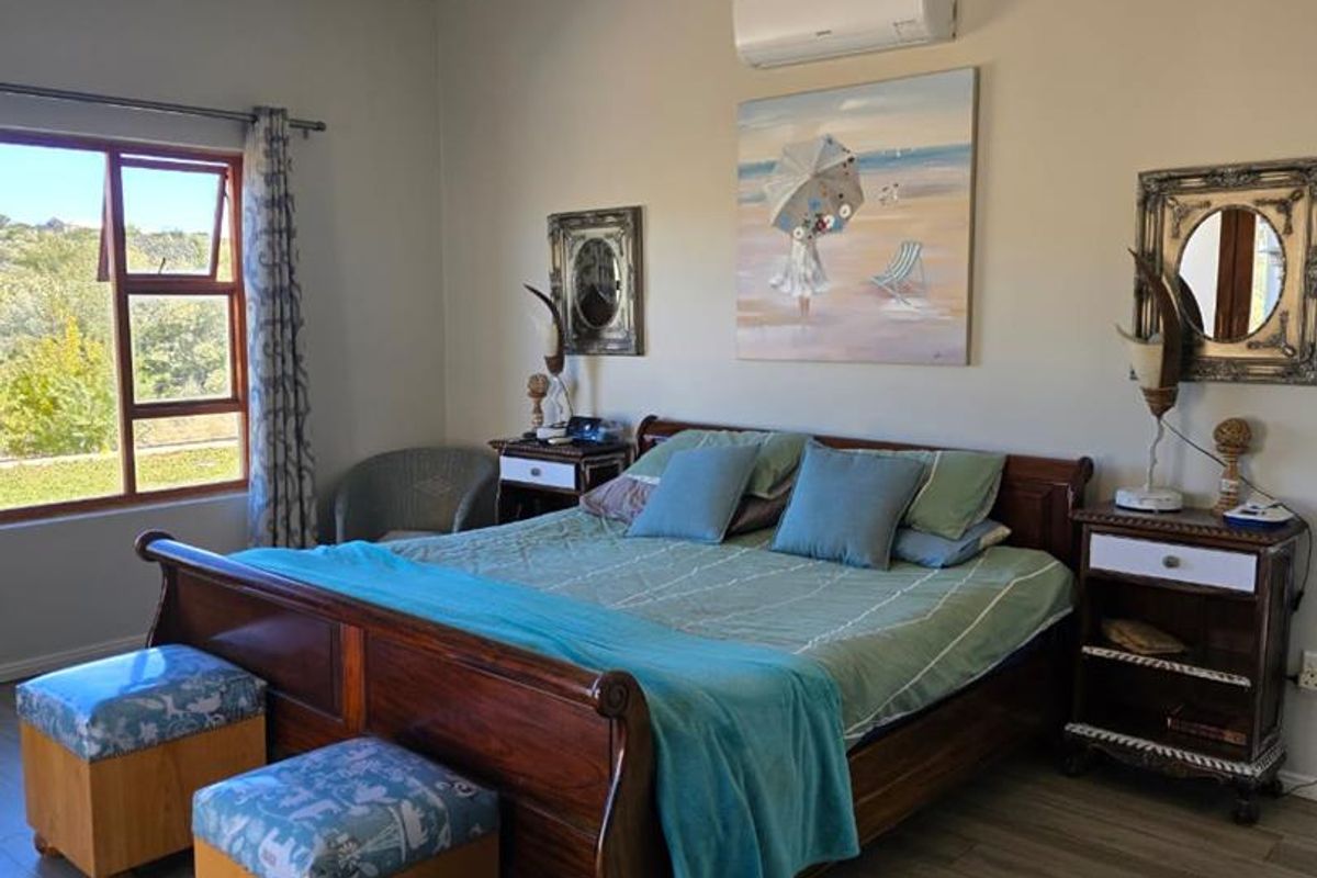 A well-maintained bedroom featuring wood-look flooring, recessed ceiling lighting, and a wall-mounted air conditioning unit.