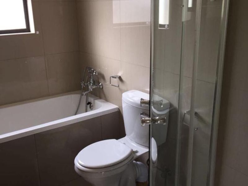 A clean, modern bathroom featuring a bathtub, separate shower enclosure, and neutral wall and floor tiling.