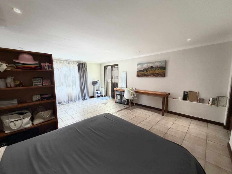 Spacious bedroom featuring neutral tiled flooring, recessed lighting, and a sliding glass door providing access to the exterior.