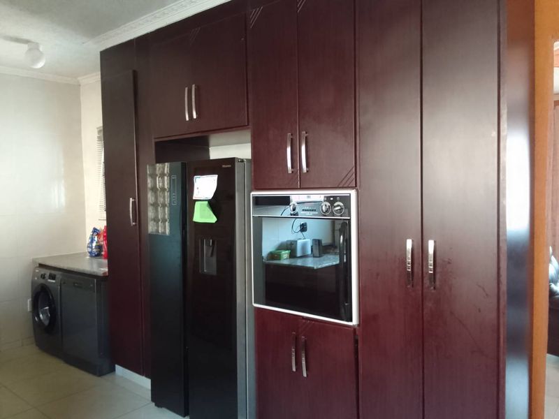 A functional kitchen featuring dark wood-finish built-in cabinetry, integrated oven, and tiled flooring with ample storage space.