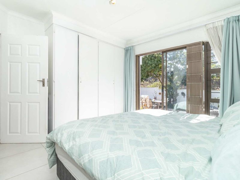 A bright bedroom featuring built-in cupboards, tiled flooring, and a sliding glass door providing direct access to the outdoor area.