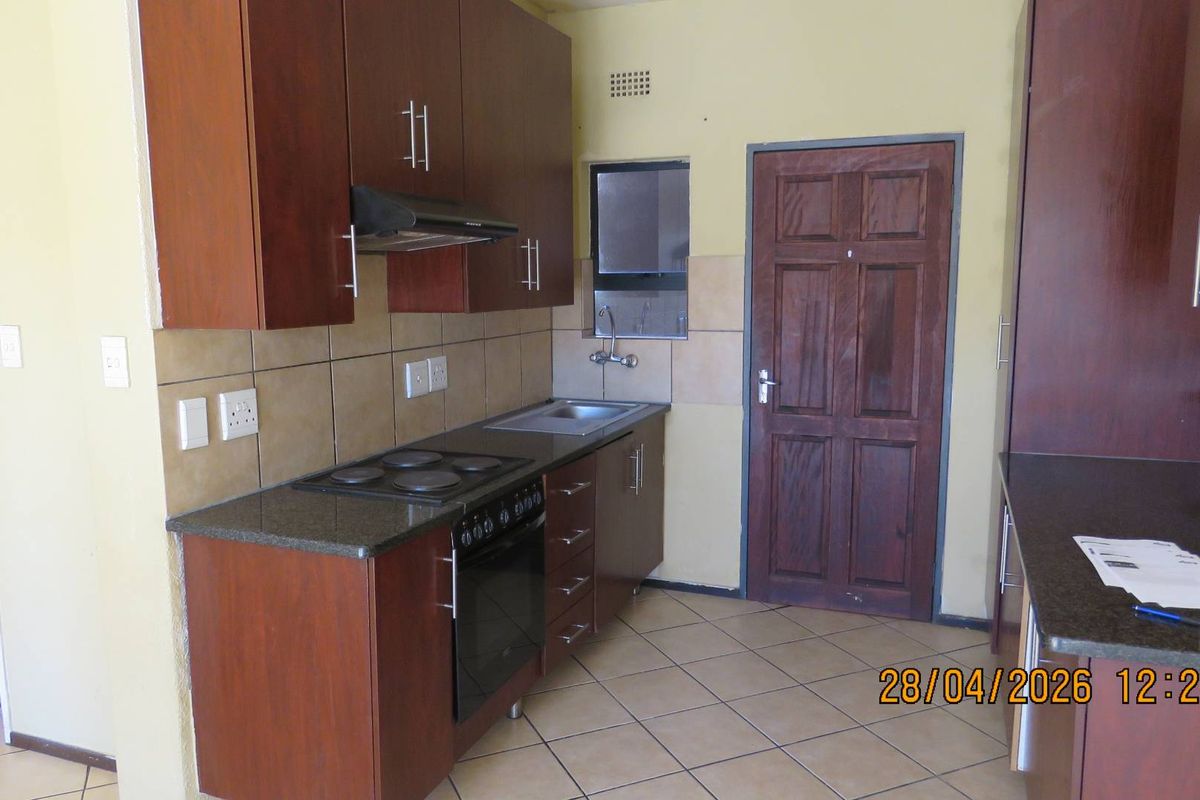 A functional kitchen featuring dark wood cabinetry, granite countertops, built-in oven and hob, and tiled flooring.