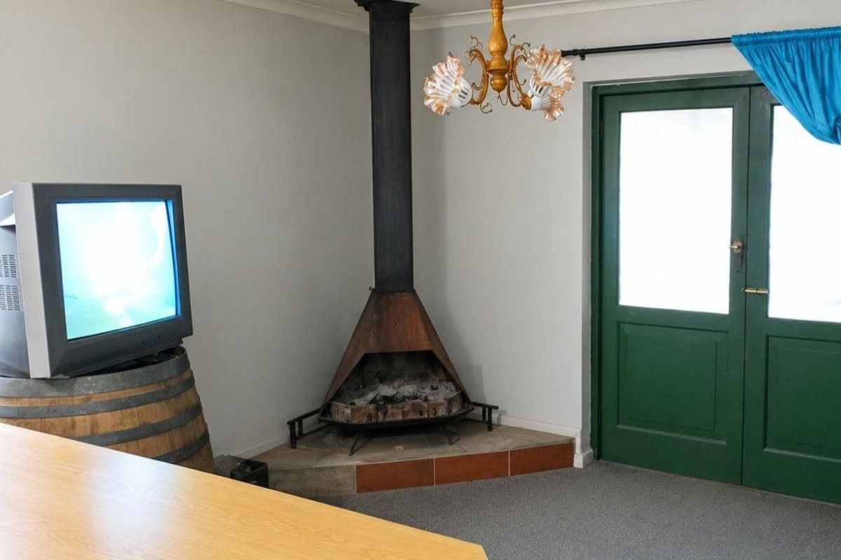 Living room featuring a corner fireplace with a metal hood, carpeted flooring, and double doors providing access to the exterior.