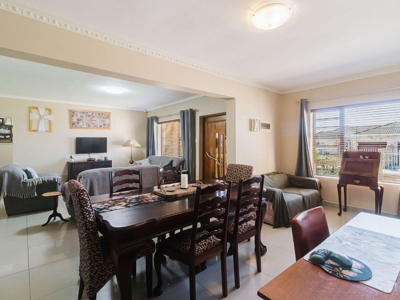 Spacious open-plan living and dining area featuring tiled flooring, decorative ceiling cornices, and large windows providing natural light.
