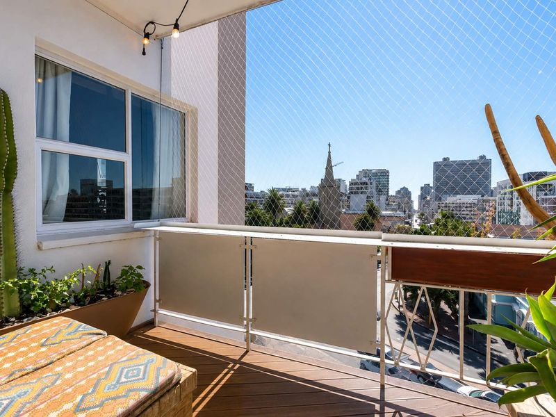 A well-maintained apartment balcony featuring modern decking, safety netting, and clear urban views.