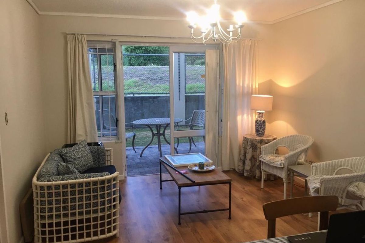 A living room featuring laminate flooring and a sliding glass door providing access to an outdoor patio area.