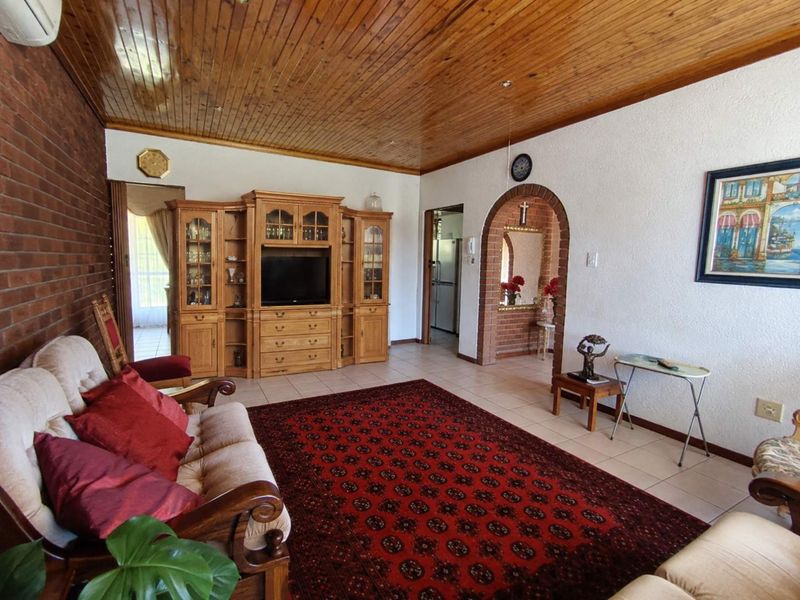 Spacious living room featuring a timber ceiling, exposed brick wall, and a classic brick archway leading to adjacent areas.