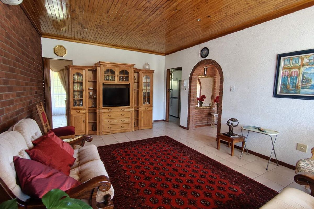 Spacious living room featuring a timber ceiling, exposed brick wall, and a classic brick archway leading to adjacent areas.