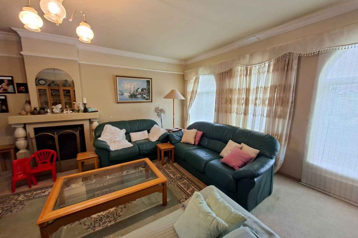 A traditional living room featuring a built-in fireplace with a decorative mantelpiece, crown molding, and large windows with integrated curtain pelmets.