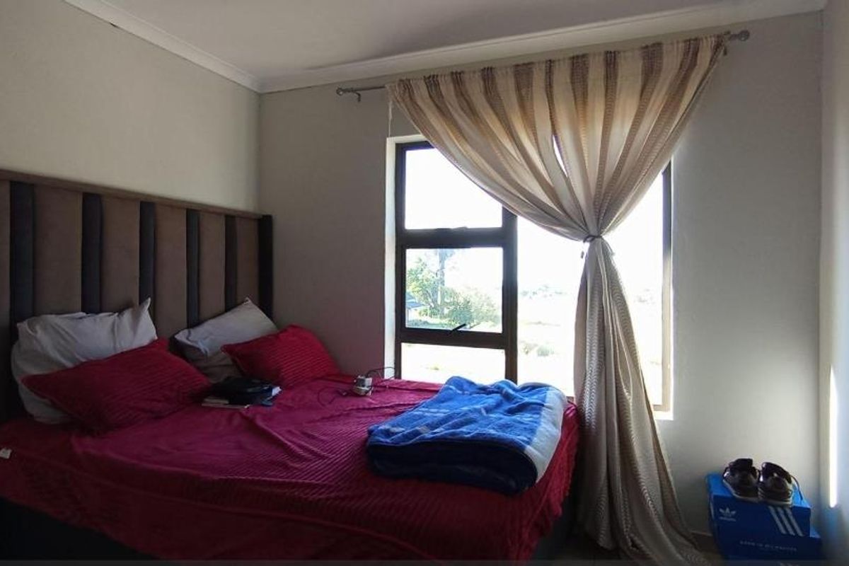 A bedroom featuring a large window with natural light, neutral wall tones, and a built-in curtain rail.
