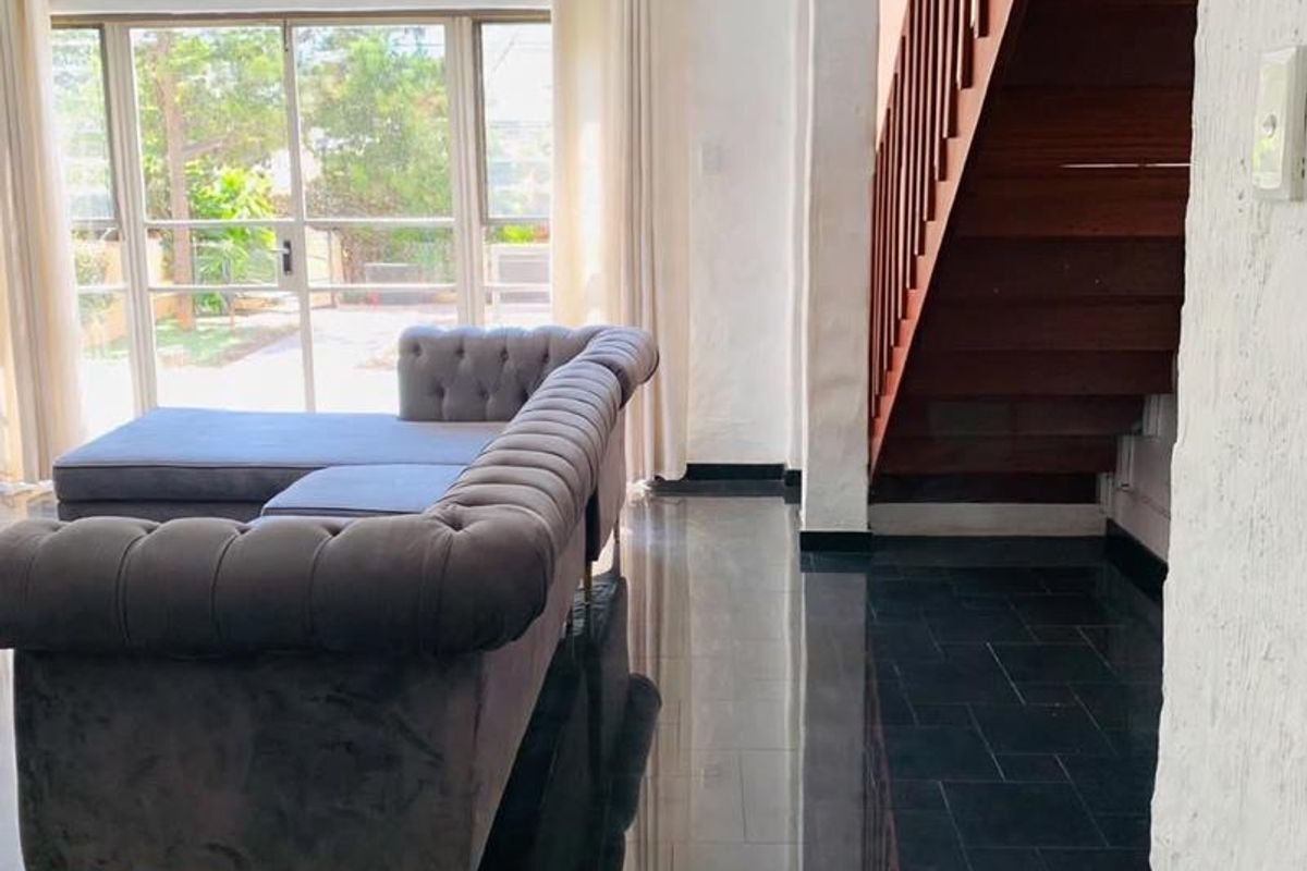 Living room featuring dark tiled flooring, a wooden staircase with balustrades, and large sliding glass doors providing access to the outdoor area.