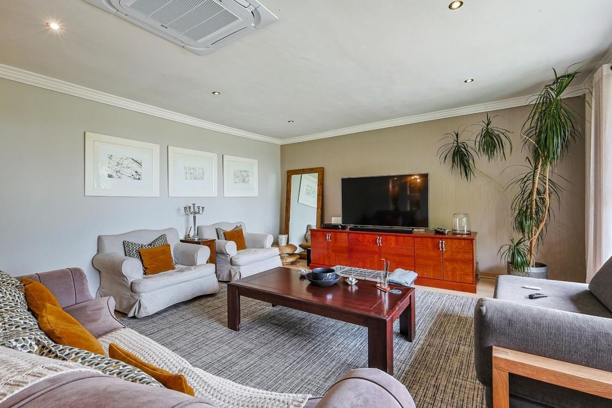 A well-maintained living room featuring recessed ceiling lighting, a built-in cassette air conditioning unit, and crown molding.