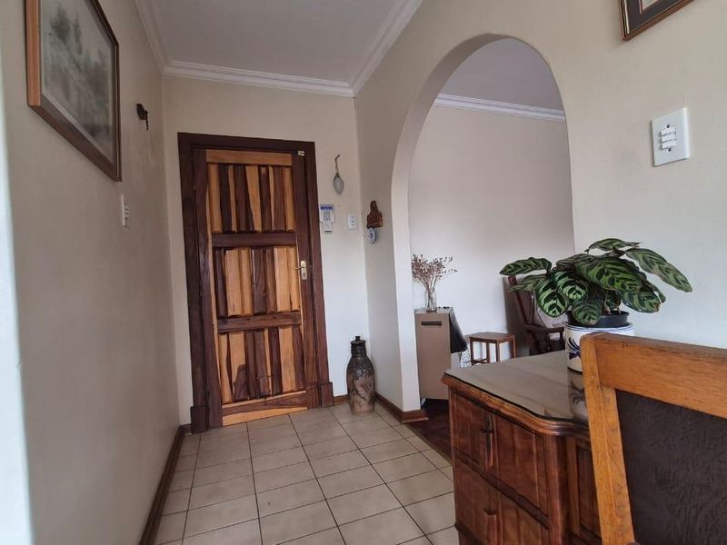 A tiled hallway featuring a distinctive timber door and an arched entryway leading into the adjacent living space.