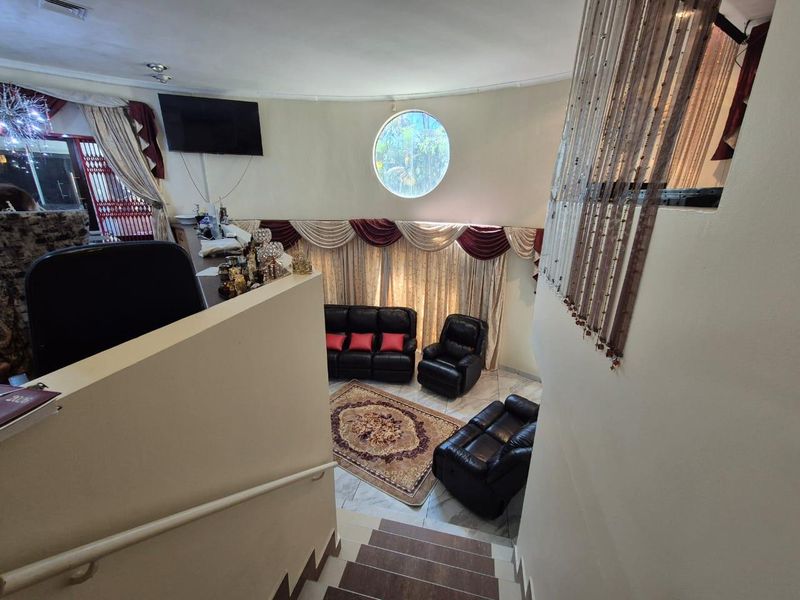 A sunken living room area featuring a distinctive circular window, tiled flooring, and direct access via a staircase with a handrail.