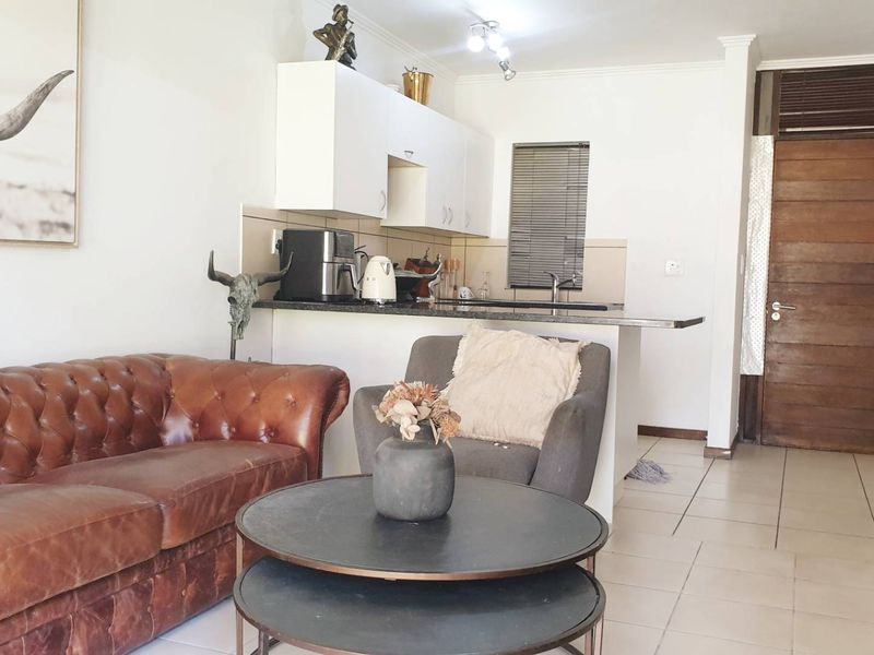 Open-plan living area featuring a compact kitchen with granite countertops and tiled flooring, seamlessly connected to the main living space.