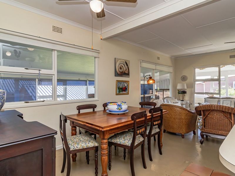 Spacious open-plan living and dining area featuring large windows, ceiling fans, and direct access to an enclosed patio space.