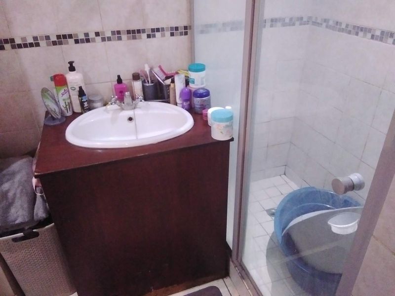 A functional bathroom featuring a vanity cabinet with a basin and a separate shower enclosure with tiled finishes.