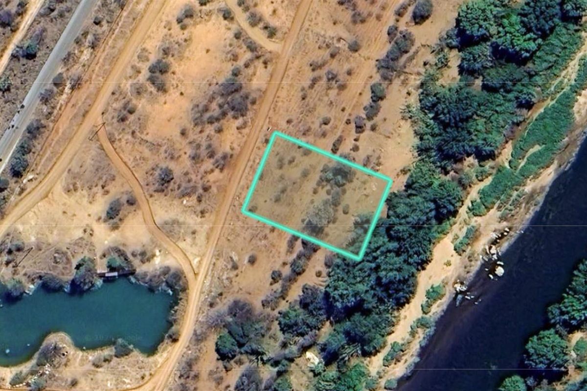 Aerial view of a vacant residential plot featuring natural vegetation and direct river frontage, ideal for development.