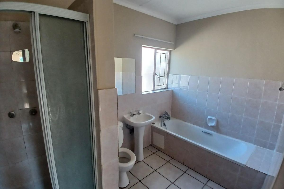 A functional bathroom featuring a separate shower enclosure, pedestal basin, and a built-in bathtub with tiled walls and flooring.