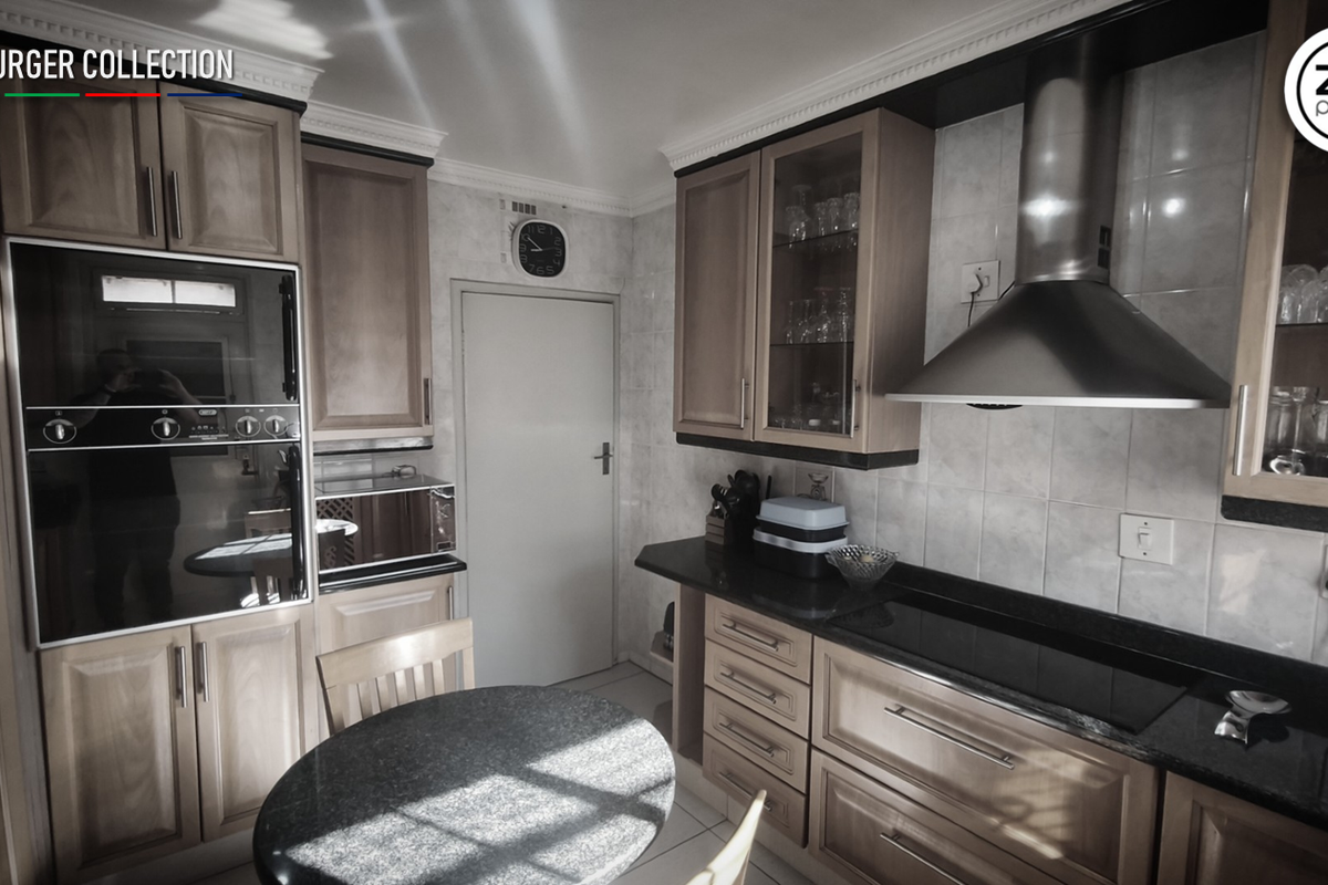 A functional kitchen featuring wooden cabinetry, granite countertops, a built-in oven, and a stainless steel extractor fan with tiled splashbacks.
