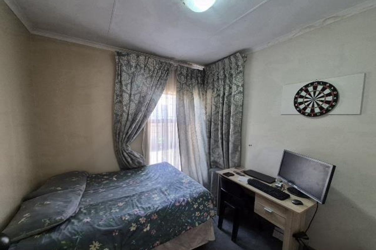 A compact bedroom featuring a window with curtain tracks and a central ceiling light fixture, requiring cosmetic updates to improve the overall finish.