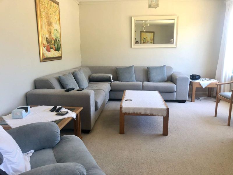 A comfortable living room featuring neutral wall tones, carpeted flooring, and decorative coving, providing a functional and inviting space for relaxation.